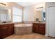 Bright bathroom featuring a garden tub, double vanities, granite countertops, and tiled floors at 8511 White Poplar Dr, Riverview, FL 33578