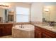 Bright bathroom featuring a garden tub, double vanities, granite countertops, and tiled floors at 8511 White Poplar Dr, Riverview, FL 33578