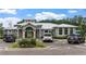 View of the clubhouse with a metal roof, stone accents, landscaping, and a parking area at 8511 White Poplar Dr, Riverview, FL 33578