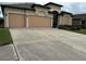 Exterior of a two-story house featuring a large driveway and a two-car garage with storm protection at 8511 White Poplar Dr, Riverview, FL 33578