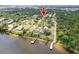 This aerial view shows a lakeside home with lush surroundings, marked by a red arrow at 9908 Alafia River Ln, Gibsonton, FL 33534