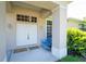 Close-up of the inviting front door, featuring a covered porch with a seating bench and well-kept landscaping at 9908 Alafia River Ln, Gibsonton, FL 33534