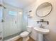 Bright bathroom featuring a glass shower door, pedestal sink, and modern round mirror at 12010 Jackson Landing Pl, Tampa, FL 33624