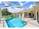 A sparkling pool with screened enclosure, next to a patio with table and chairs at 1212 Baycove Ln, Lutz, FL 33549