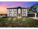 Two-story home at dusk with a two-car garage, dark trim, light siding, and arched entryway at 12470 Elgin Blvd, Spring Hill, FL 34609