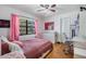 Bright bedroom features a window with pink curtains, ceiling fan, closet, desk, and hardwood floors at 14169 Fennsbury Dr, Tampa, FL 33624