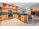 Bright kitchen featuring wood cabinetry, granite countertops, stainless steel appliances and an adjoining living room at 14169 Fennsbury Dr, Tampa, FL 33624