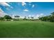 View of golf course with meticulously maintained green fairways, flags, and palm trees at 1516 E Lake Woodlands Pkwy, Oldsmar, FL 34677