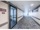 Hallway featuring carpeted floors, neutral walls with grey accents and view of exit doors at 1516 E Lake Woodlands Pkwy, Oldsmar, FL 34677