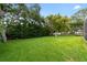 Large green backyard featuring lush landscaping and a screened-in pool, offering a private outdoor retreat at 1562 Coastal Pl, Dunedin, FL 34698