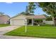 Charming single-story home with a well-maintained lawn, attached garage, and inviting front porch at 1562 Coastal Pl, Dunedin, FL 34698