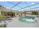 An inviting backyard pool area featuring a spacious patio, seating, bar and screened-in pool at 1562 Coastal Pl, Dunedin, FL 34698