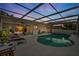 Enjoy outdoor living with a screened-in pool, lounge area, and beautiful lighting for evening relaxation at 1562 Coastal Pl, Dunedin, FL 34698