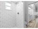 Bright shower featuring white subway tiles, a rain shower head, and a view of the adjacent bathroom at 1562 Coastal Pl, Dunedin, FL 34698