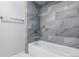 Bathroom featuring marble-look tile and a tub with a shower at 16109 Rambling Vine E Dr, Tampa, FL 33624