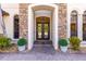 Inviting entryway with ornate double doors, stone archway, decorative plants, and a brick path leading to the entrance at 17301 Ladera Estates Blvd, Lutz, FL 33548