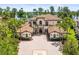 Elegant two-story home showcasing a well-manicured lawn, palm trees, and a circular driveway with a unique brick design at 17301 Ladera Estates Blvd, Lutz, FL 33548