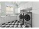 Well-lit laundry room with modern appliances, ample counter space, and classic black and white flooring at 17301 Ladera Estates Blvd, Lutz, FL 33548