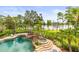 Relaxing pool area with a waterfall feature, hot tub, lounge chairs, and picturesque views of the serene lake at 17301 Ladera Estates Blvd, Lutz, FL 33548