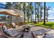 Serene backyard patio with seating area, fire pit, and lush landscaping leading to the lake at 18258 Wayne Rd, Odessa, FL 33556