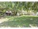 Lush backyard with mature trees, covered patio, and seating area, perfect for outdoor relaxation at 2704 Dorene Dr, Plant City, FL 33563