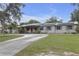 Charming single-story home featuring a concrete driveway, solar panels, and lush front lawn at 2704 Dorene Dr, Plant City, FL 33563