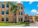 Exterior view of a multi-story building with light peach facade, dark windows, and lush landscaping at 2773 Via Cipriani # 1310A, Clearwater, FL 33764