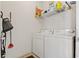 Functional laundry room with white washer and dryer, upper shelving, and cleaning supplies at 2773 Via Cipriani # 1310A, Clearwater, FL 33764