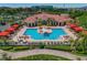 Aerial view of a community pool area with lounge chairs, red cabanas, and lush landscaping at 2773 Via Cipriani # 1310A, Clearwater, FL 33764