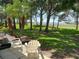 Relaxing backyard with patio, chairs, mature trees, and lush green grass at 303 Meadow Ln, Oldsmar, FL 34677