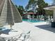 Community pool with ample seating, surrounded by lush greenery and palm trees at 303 Meadow Ln, Oldsmar, FL 34677