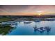 This gorgeous aerial view shows the community pool, beach area, water obstacle course, and surrounding neighborhood at sunset at 31483 Cardinal Yard Dr, San Antonio, FL 33576