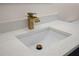 Close-up of a bathroom sink with white countertop and a gold faucet, showcasing modern design and elegant fixtures at 3709 Danny Bryan Blvd, Tampa, FL 33619