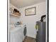 Functional laundry room equipped with a washer, dryer, and shelving for storage, alongside the water heater at 4017 Cedar Limb Ct, Tampa, FL 33614