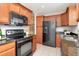 Open kitchen featuring modern appliances, granite countertops, tile floors and natural wood cabinets at 4234 Brentwood Park Cir, Tampa, FL 33624