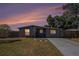 Charming single-story home with a well-manicured lawn and a private driveway, set against a colorful dusk sky at 4521 W North St, Tampa, FL 33614