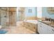 Bright bathroom features a glass shower, bathtub, vanity, and granite countertop at 5156 Pinnacle Dr, Oldsmar, FL 34677