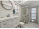 This is a bathroom with a glass shower, toilet, and vanity with a round mirror at 60 Lakeview Ct, Palm Harbor, FL 34683