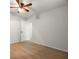 An empty bedroom with hardwood floors, white walls, a ceiling fan, and a door to the hall at 60 Lakeview Ct, Palm Harbor, FL 34683