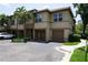 A tan two-story townhome with a brown roof, surrounded by lush tropical landscaping, including palm trees at 612 Arbor Lake Ln, Tampa, FL 33602