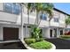 Inviting white townhome with an attached garage and decorative landscaping, including palm trees at 612 Arbor Lake Ln, Tampa, FL 33602