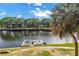 Scenic waterfront view featuring a boat docked along the canal and lush landscaping, with a view of the condos at 6309 Newtown Cir # 9B2, Tampa, FL 33615