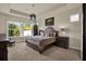 Primary bedroom featuring a trey ceiling, neutral walls, large window, and stylish furniture at 6909 Crestpoint Dr, Apollo Beach, FL 33572
