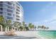 Striking view of a modern building on a white sand beach, complete with lounge chairs, umbrellas, and clear ocean waters at 805 S Gulfview Blvd # 305B, Clearwater, FL 33767