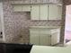 Kitchen view with dated wallpaper, tile floor, and off-white cabinets at 8130 Shalom Dr, Spring Hill, FL 34606
