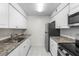 Galley kitchen features stainless appliances, granite counters and white cabinets at 9130 Tudor Dr # M105, Tampa, FL 33615