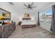 Bright main bedroom boasts a ceiling fan, a large window with gray curtains and sleek, modern wood flooring at 9647 Summers Cay Cir, Thonotosassa, FL 33592