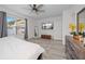 Bright main bedroom boasts a ceiling fan, TV, bench, and sleek, modern wood flooring at 9647 Summers Cay Cir, Thonotosassa, FL 33592