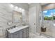 Modern bathroom featuring marble countertops, an elegant vanity, a glass-enclosed shower and bright lighting at 18258 Wayne Rd, Odessa, FL 33556
