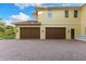 Three-car garage with a brick driveway, set against a bright blue sky at 18258 Wayne Rd, Odessa, FL 33556